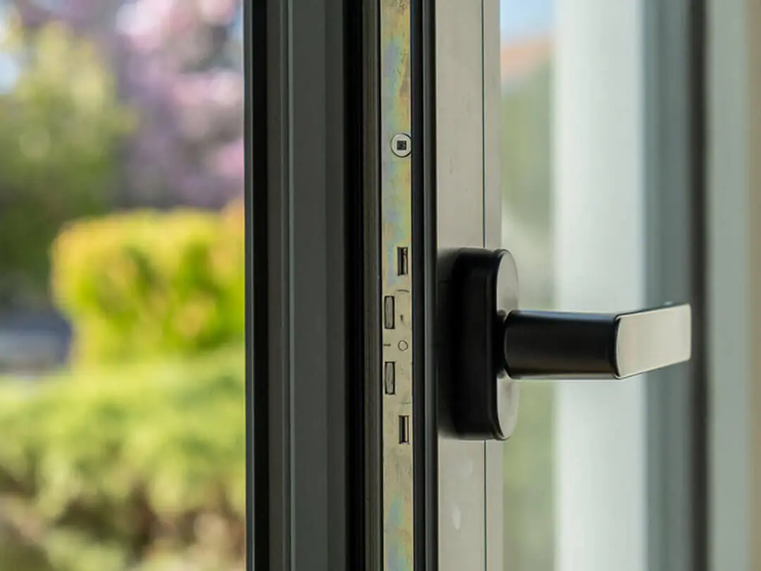 Detail van een antraciet aluminium kozijn met zwarte greep
