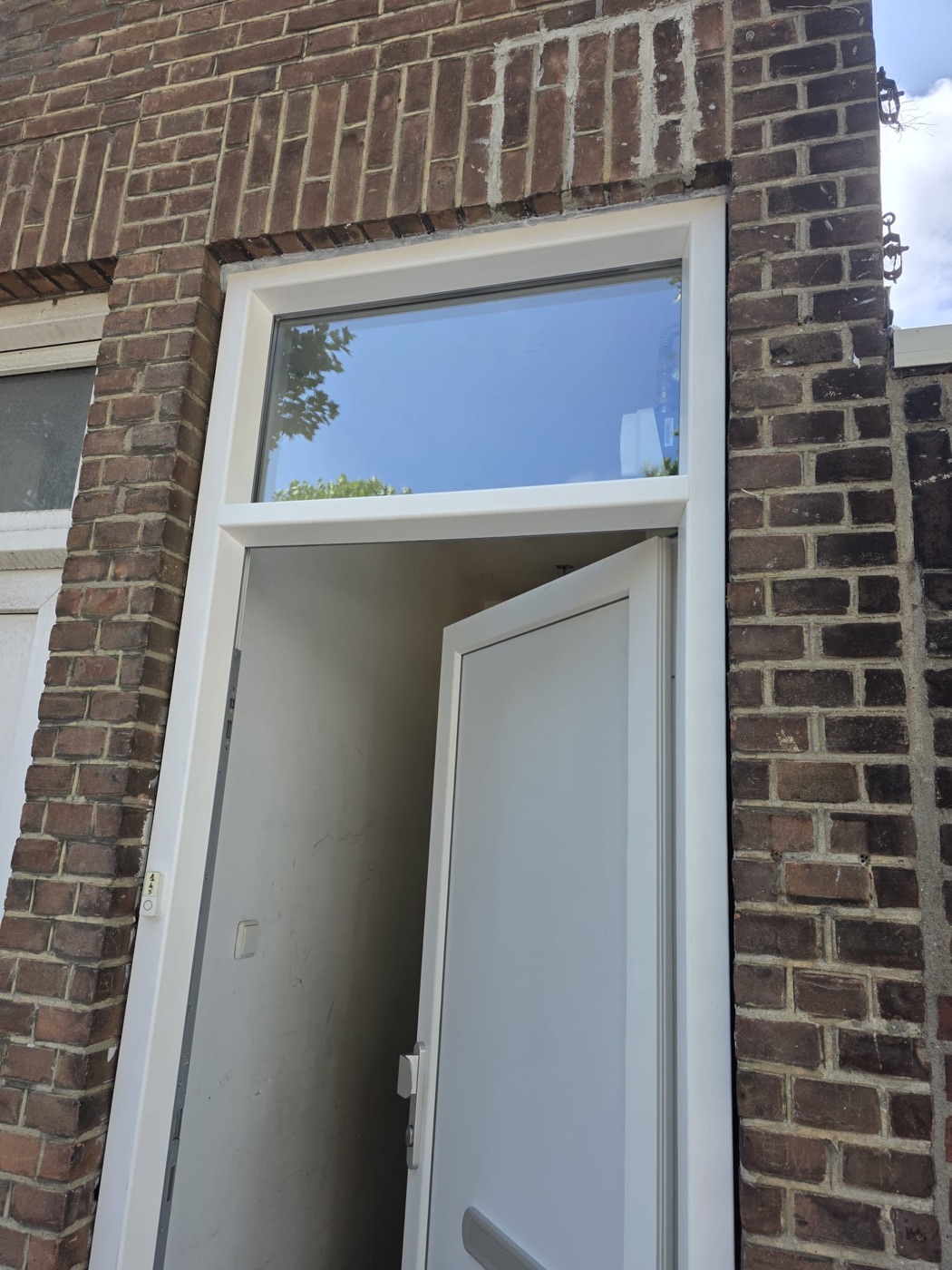 Nieuwe kunststof voordeur met bovenlicht in metselwerk