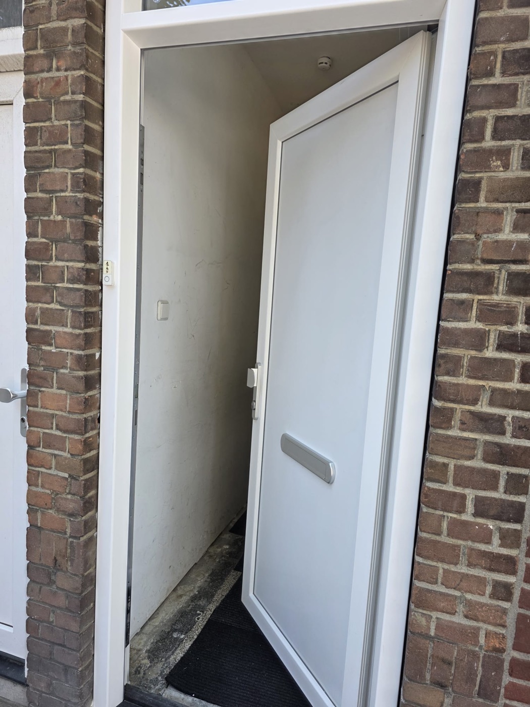 Witte kunststof voordeur in bakstenen gevel